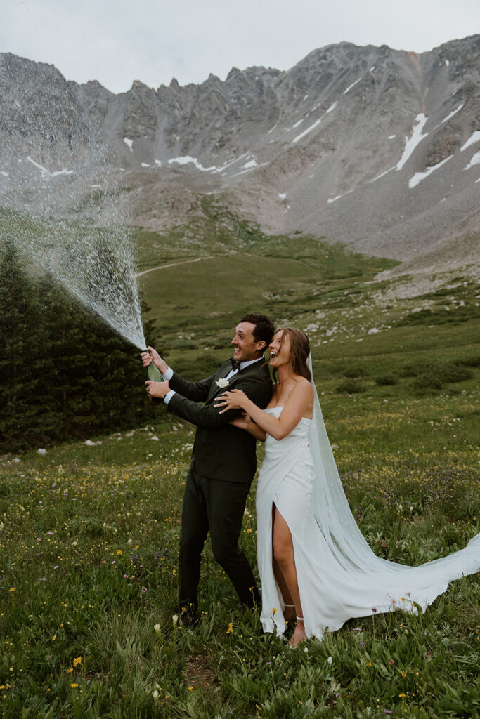 Bride and groom pop champagne at their Colorado wildflower elopement in Breckenridge