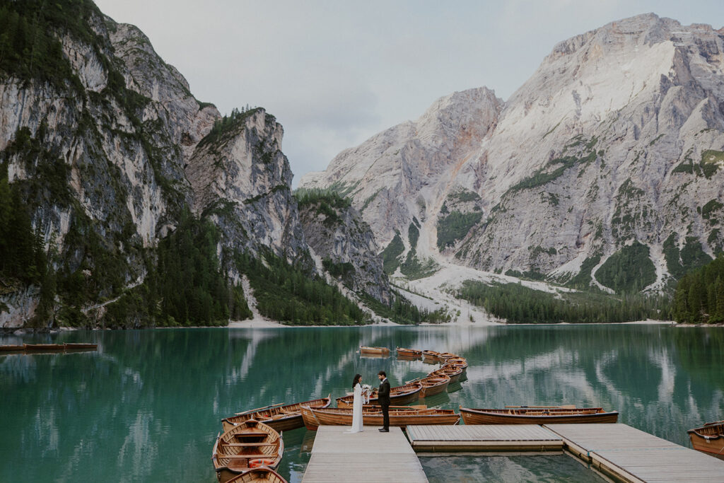 Couple stands near the iconic Lago di Braies canoes in the Dolomites