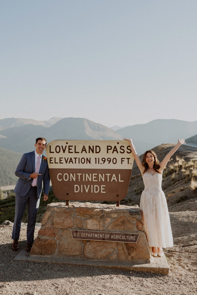 Bride and groom stand next to the Loveland Pass sign