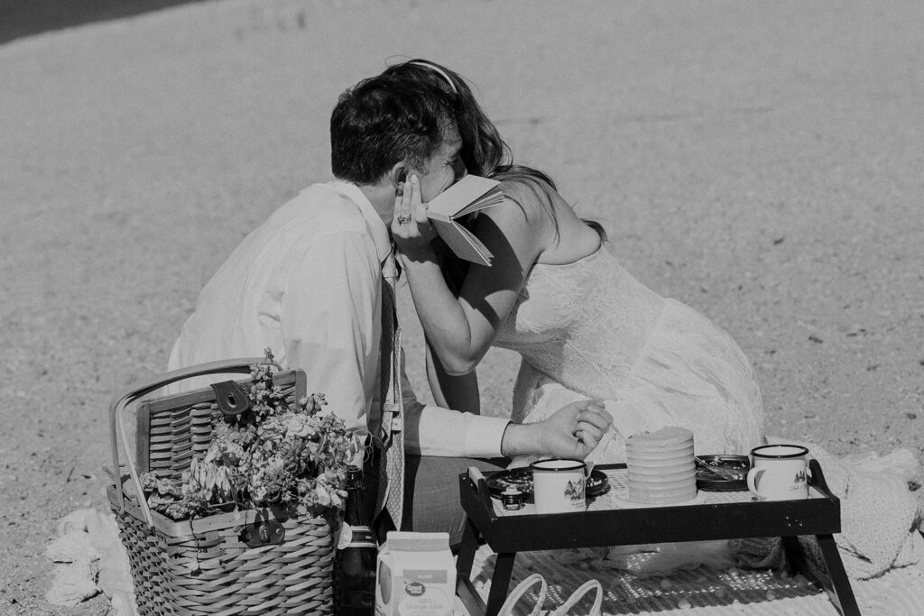 Bride and groom have cake and drinks on a lakeside in Colorado