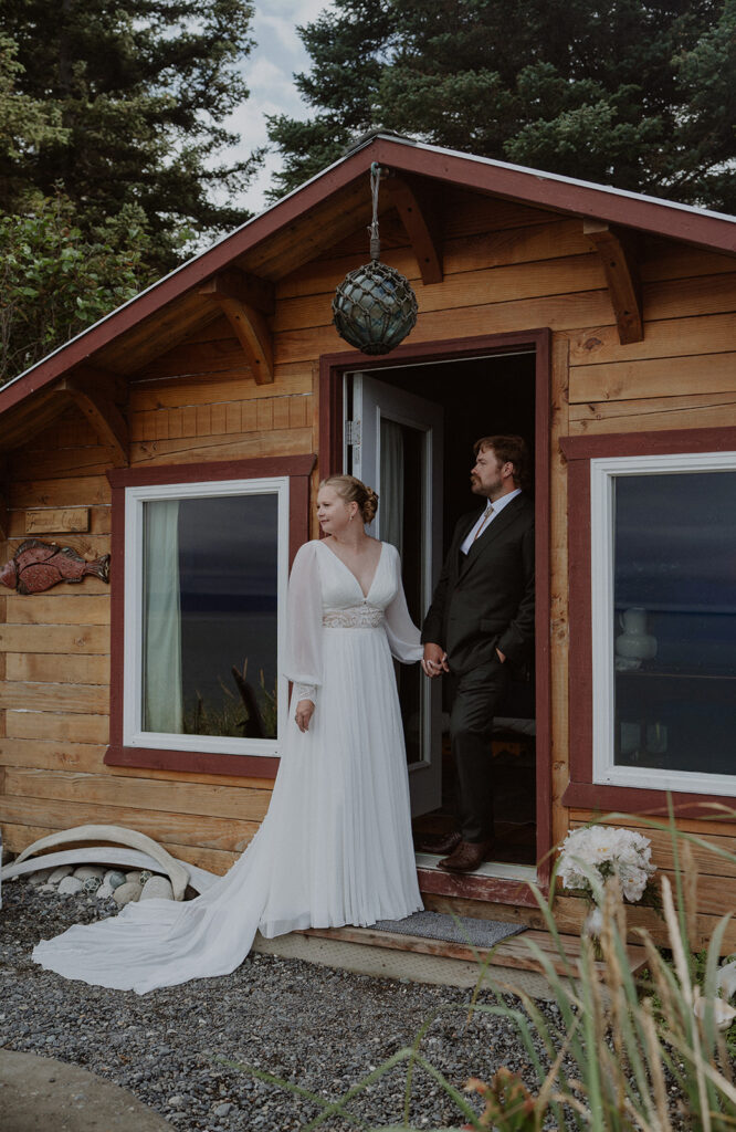 Bride and groom stand in a cabin doorway in Alaska