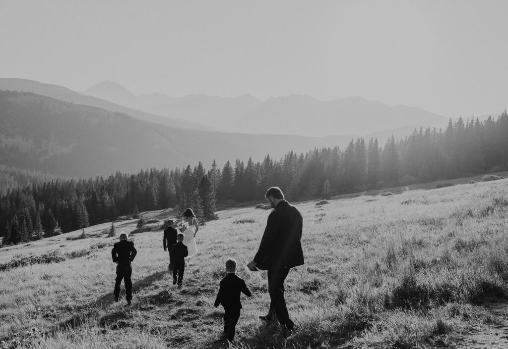 Bride groom and 4 sons walk down a meadowed hill in Breckenride, CO