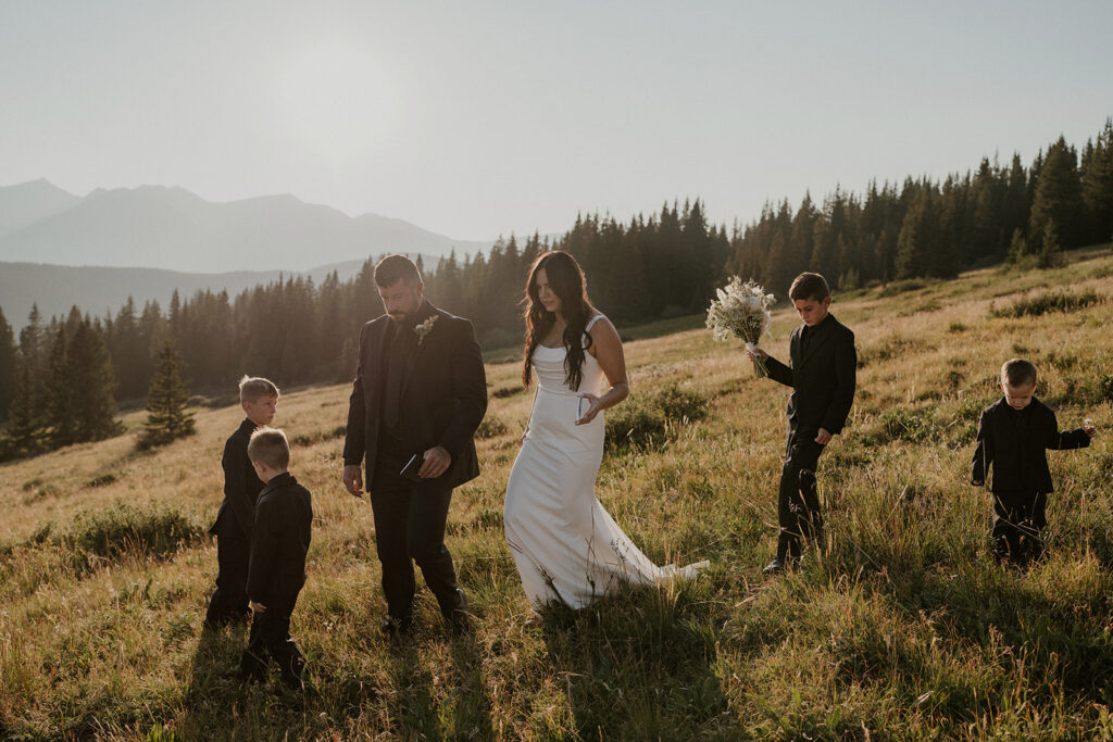 Bride groom and 4 sons walk down a meadowed hill in Breckenride, CO