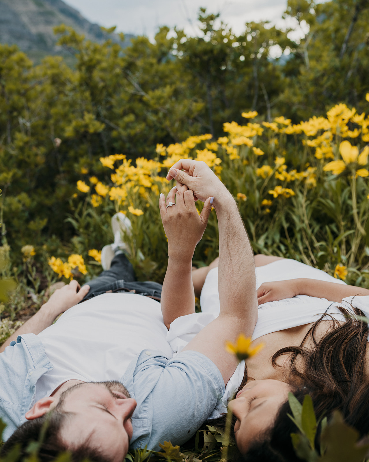 A couple lays in a field of wildflowers on a mountain trail holding hands Staunton State Park Wedding