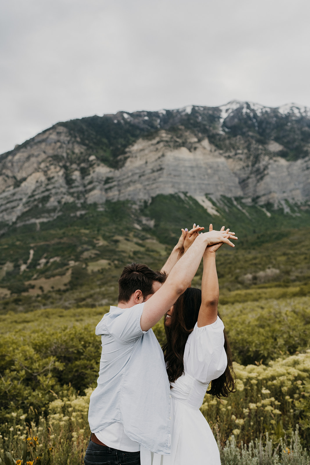 A couple holds hands together above their heads while standing on a mountain path Donovan Pavilion wedding