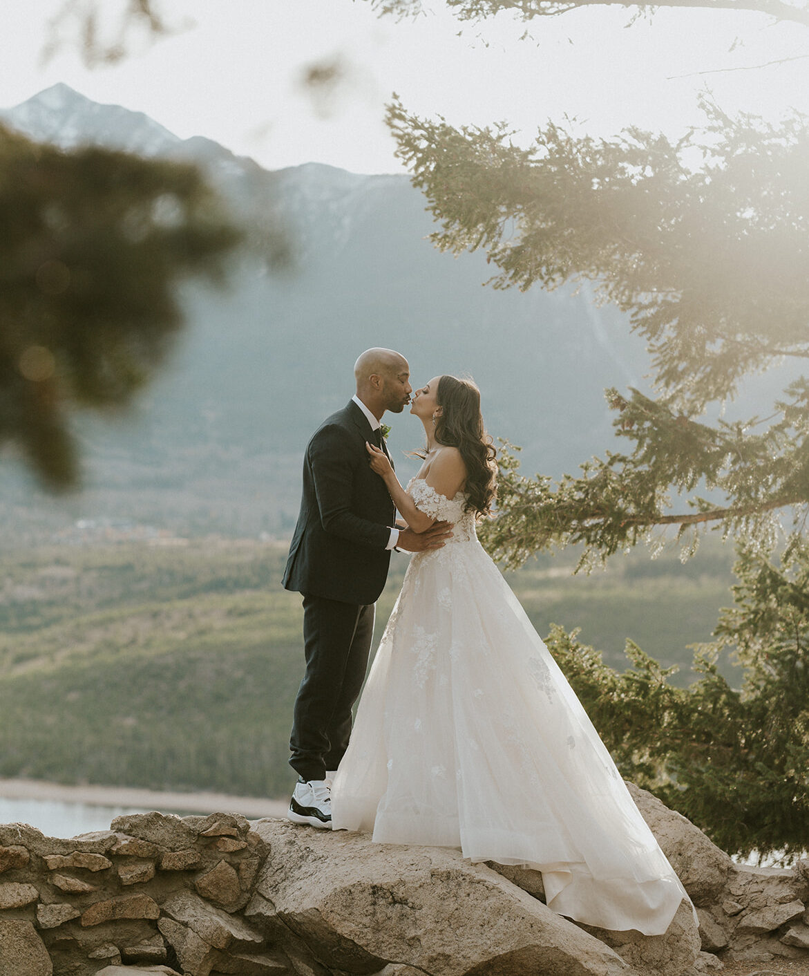 Newlyweds kiss while standing on a wall of rocks at their Cottonwood Pass elopement