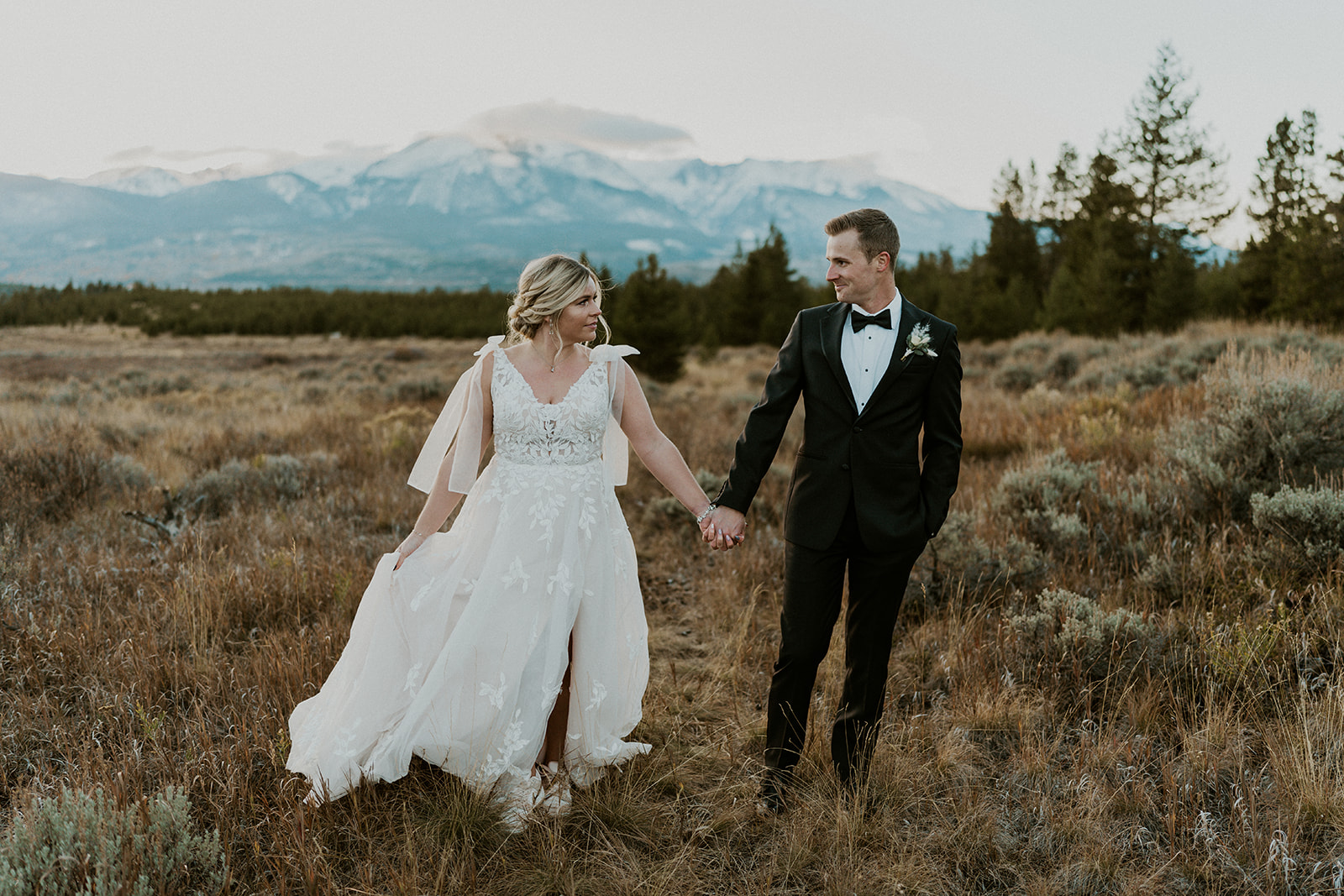 Newlyweds hold hands while walking down a trail in the mountains to their Loveland Pass Elopement