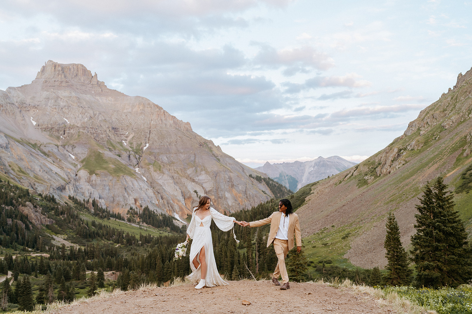 Newlyweds hold hands while walking on a mountain trail during their Ouray Elopement