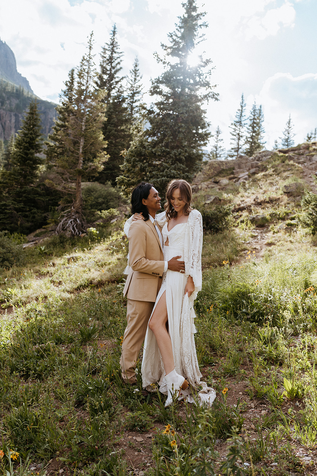 Newlyweds shore an intimate moment with smiles at sunset on a remote hillside