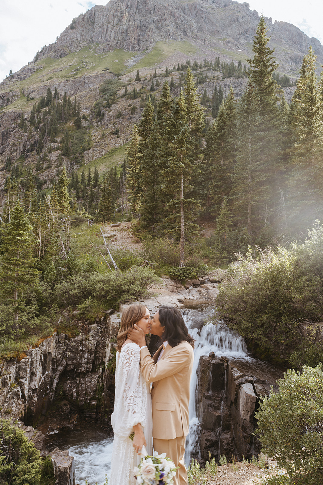 Newlyweds kiss in front of a waterfall during their Ouray Elopement