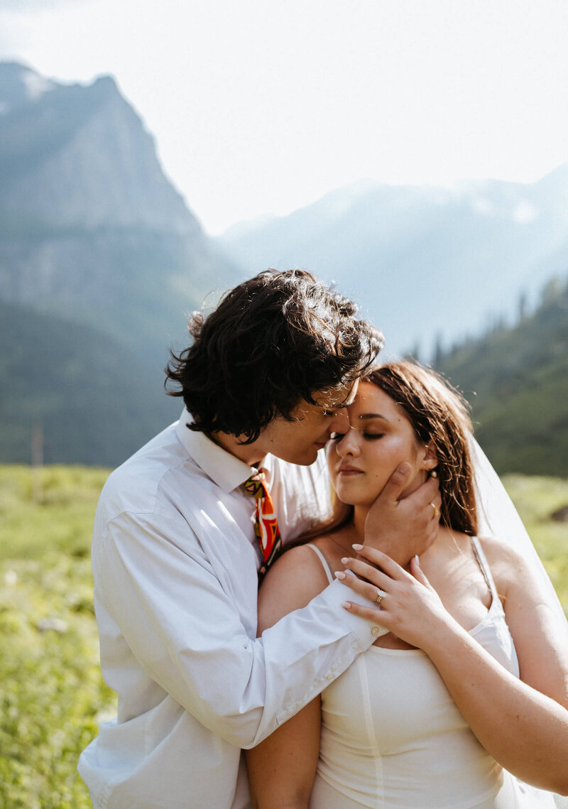 Newlyweds kiss while standing on a hill in the mountains at their telluride elopement