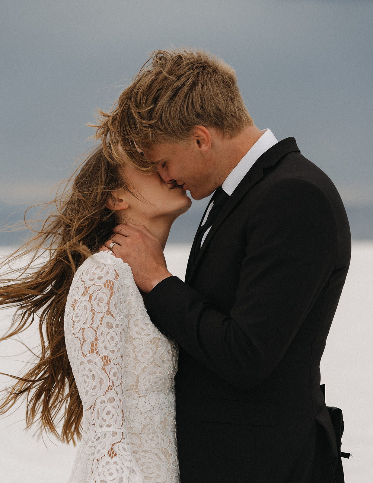 NEwlyweds kiss in a black suit and white lace dress