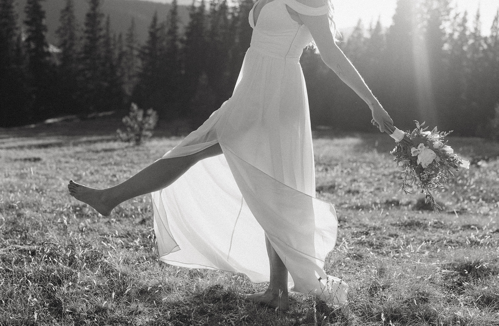 A bride dances and walks through a remote field barefoot Colorado Adventure Elopement