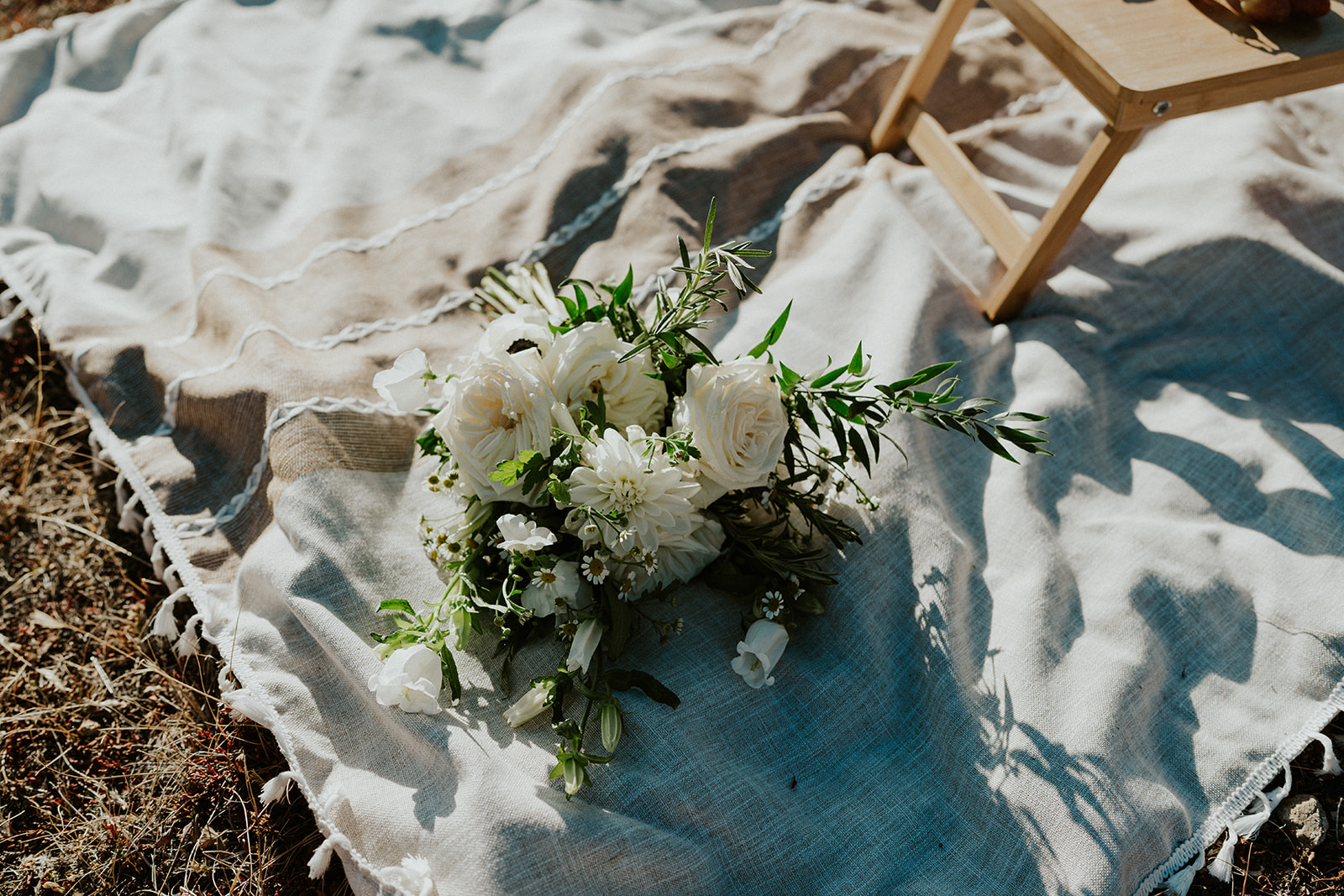 Details of a white rose bouquet on a picnic blanket during a Colorado Helicopter Wedding