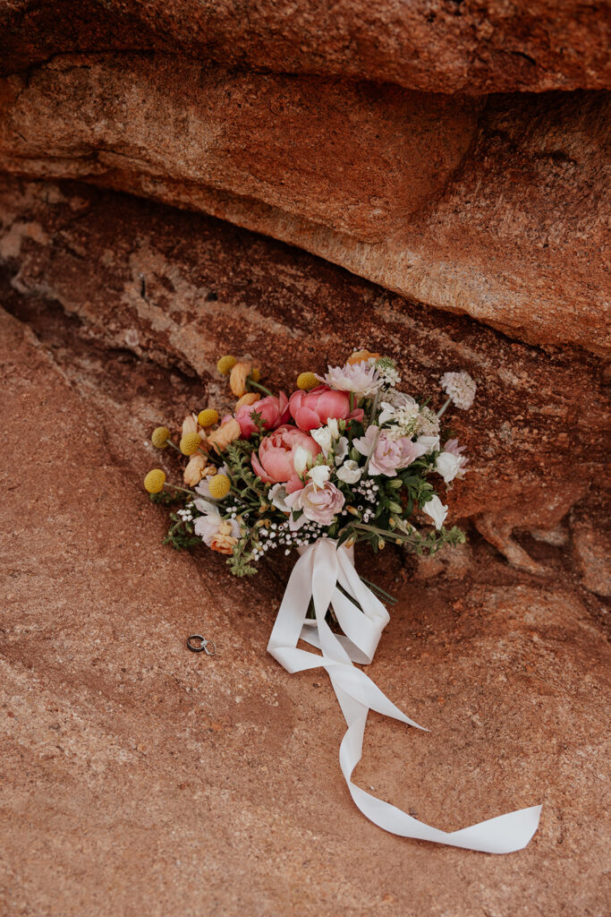 Organic spring wedding bouquet laying on rocks in Garden of The Gods, Colorado.