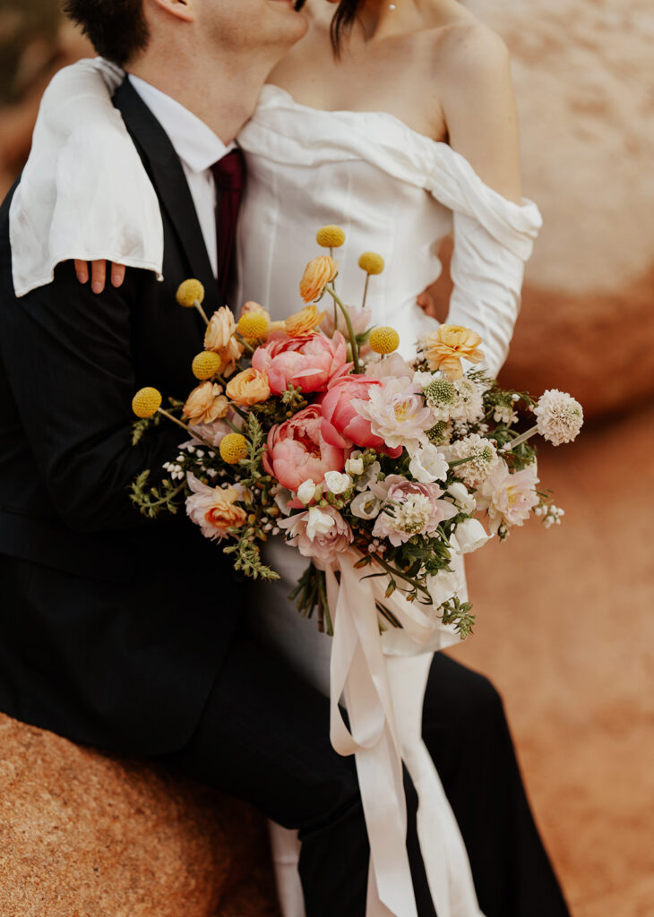 Close up shot of a groom holding his bride as she holds her spring wedding bouquet 