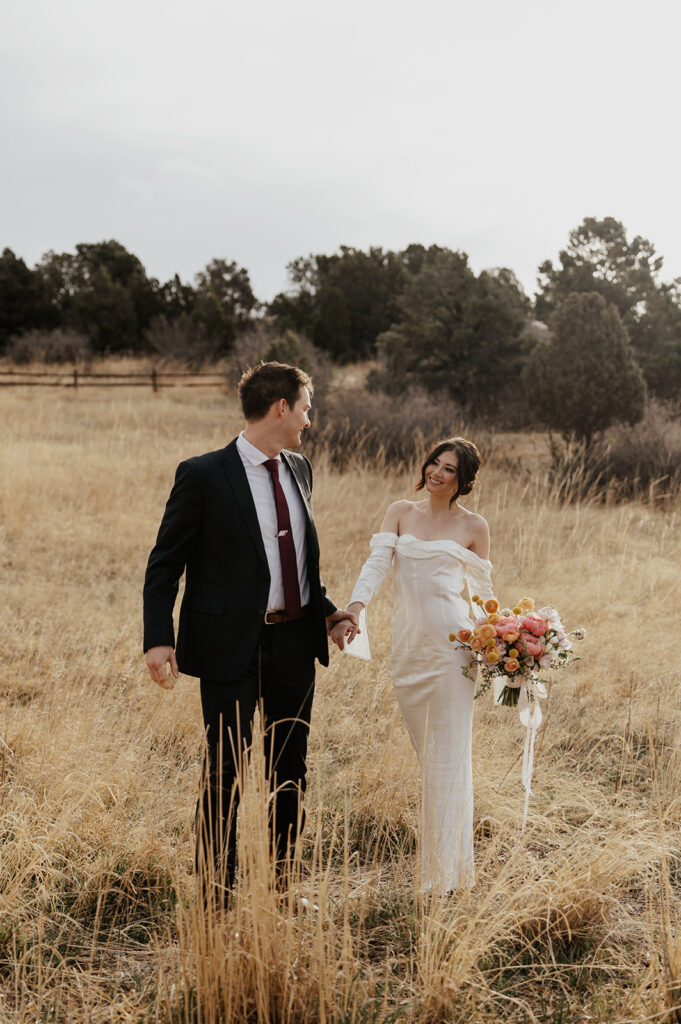 Bride and groom posing for portraits in an open field