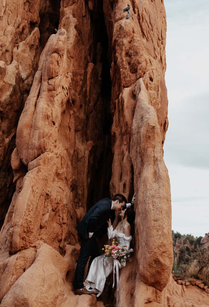 Bride and groom sitting in a red rock formation in Garden of The Gods for their Colorado Springs elopement