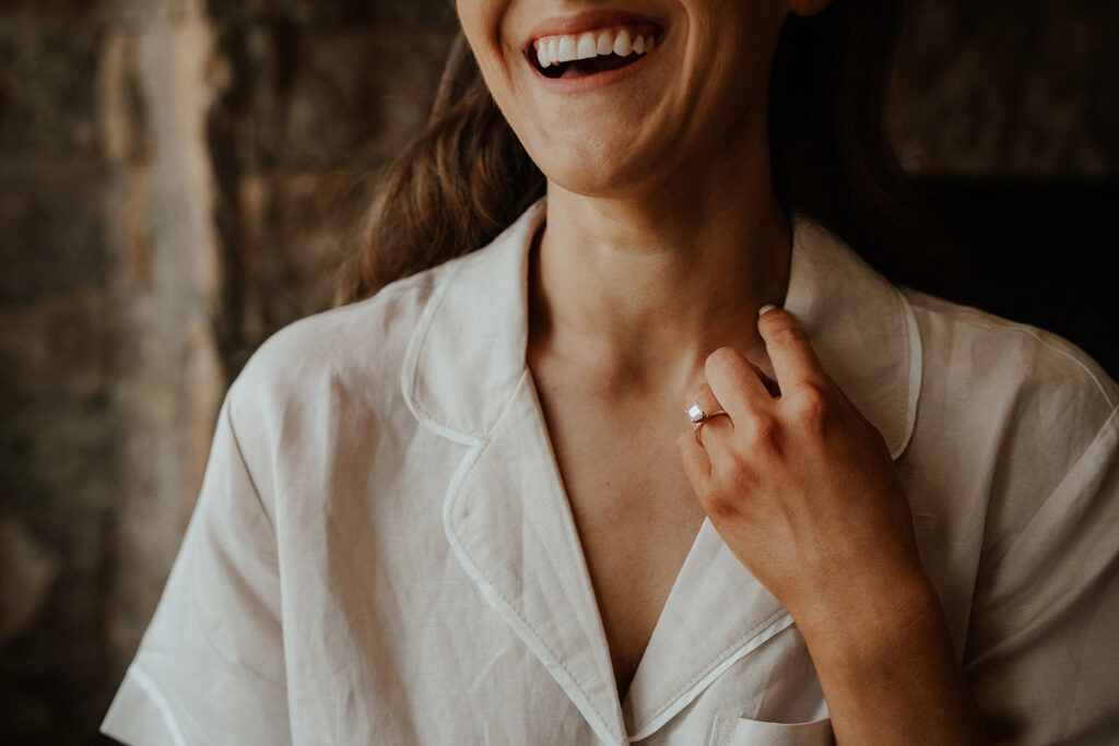 Bride laughing as she holds up her hand with her engagement band showing