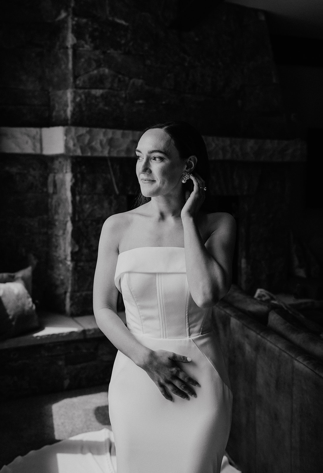 Black and white photo of a bride touching her earrings during her indoor bridal portraits at Northwoods for her intimate Airbnb elopement in Breckenridge, Colorado