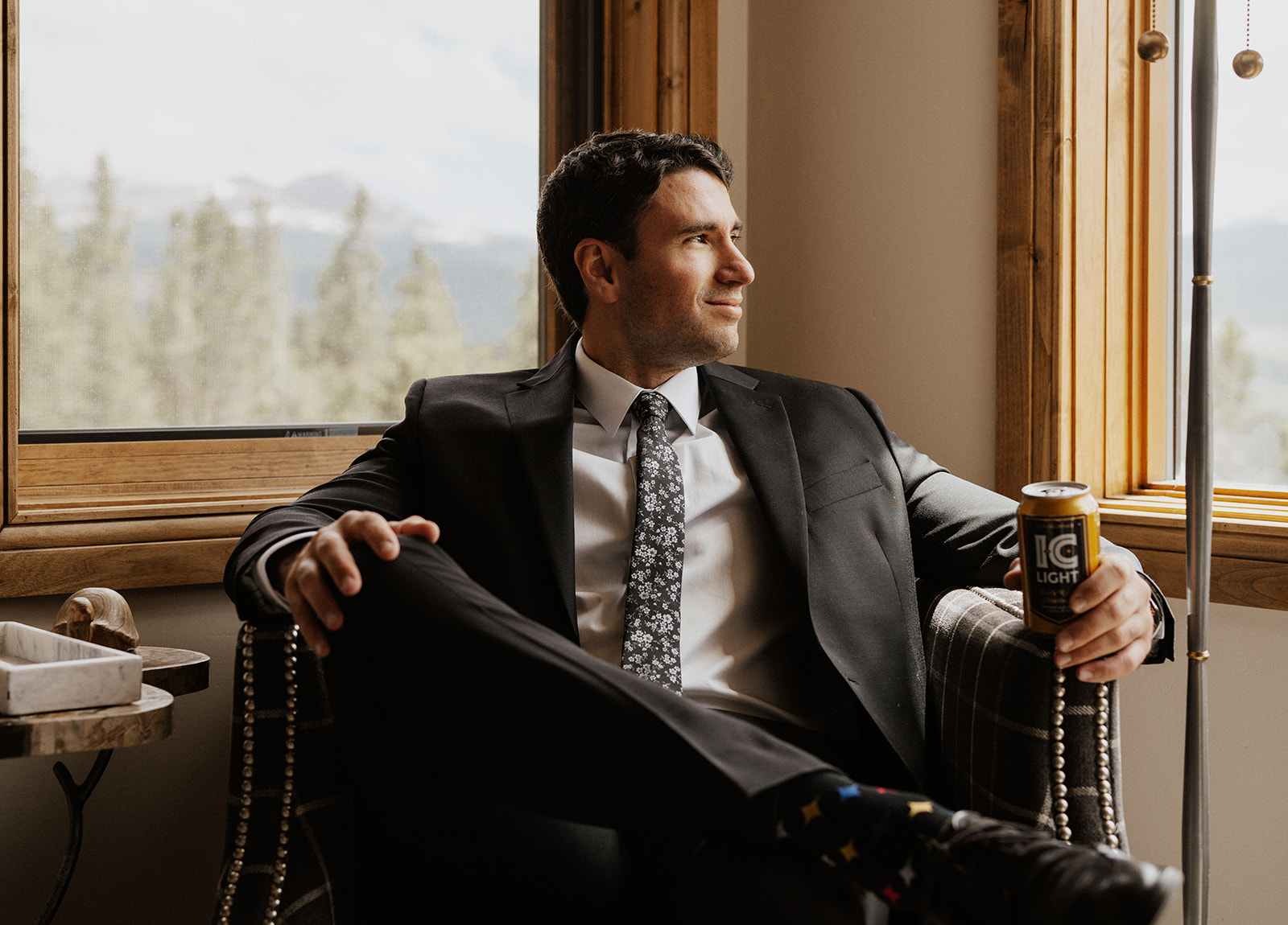 Groom sitting in a chair with a beer before his Airbnb elopement in Breckenridge, Colorado at Northwoods