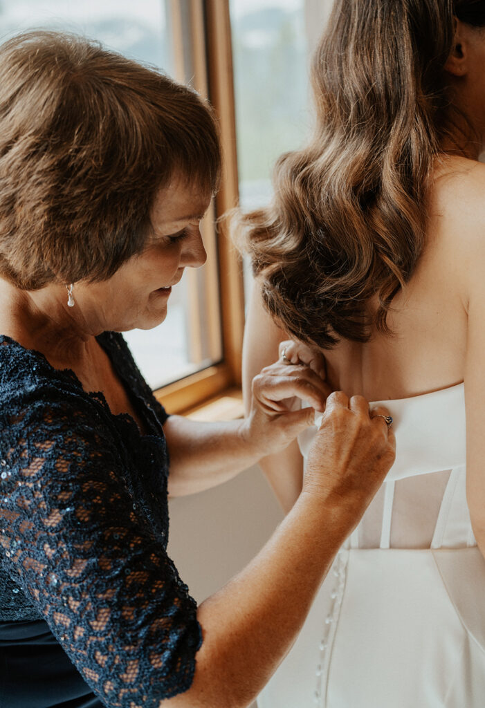 Brides mother buttoning up her wedding dress