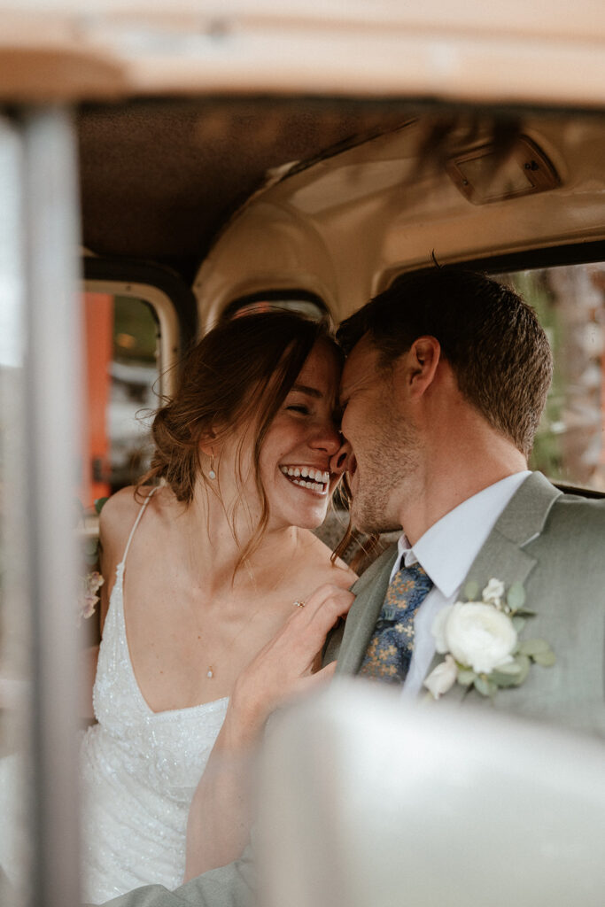 Bride and groom laughing while they sit in an old Chevy truck