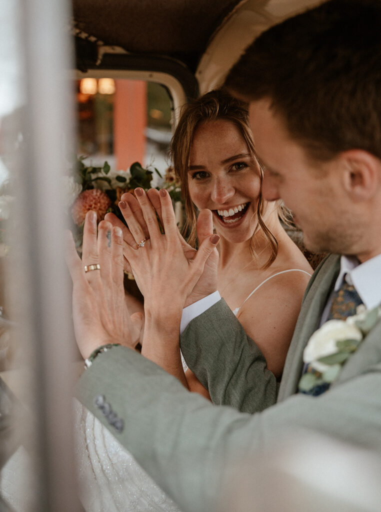 Bride and groom sitting in an old Chevy truck showing off their wedding rings