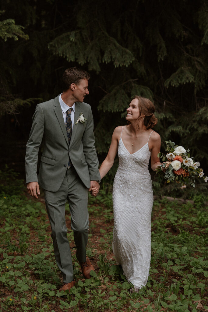 Bride and groom walking through a woodsy area during their elopement