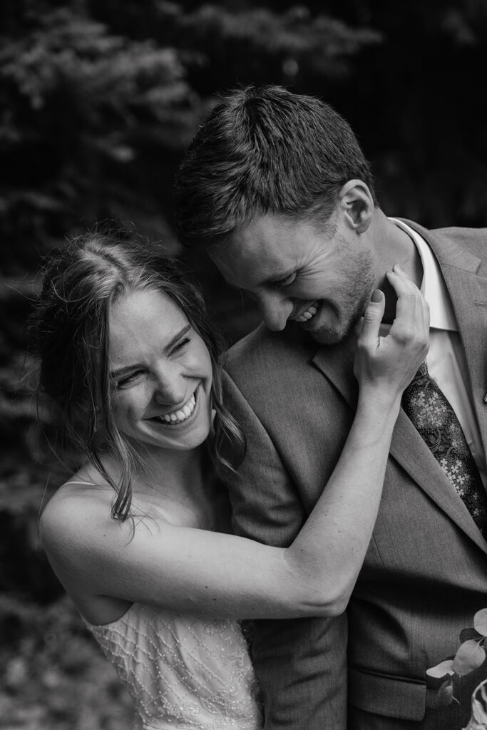 Black and white candid photo of a bride and groom laughing