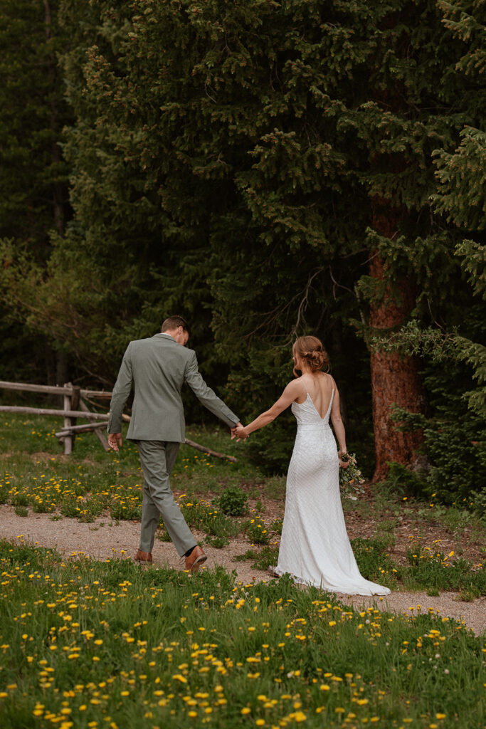 Bride and groom holding hands and walking up a trail