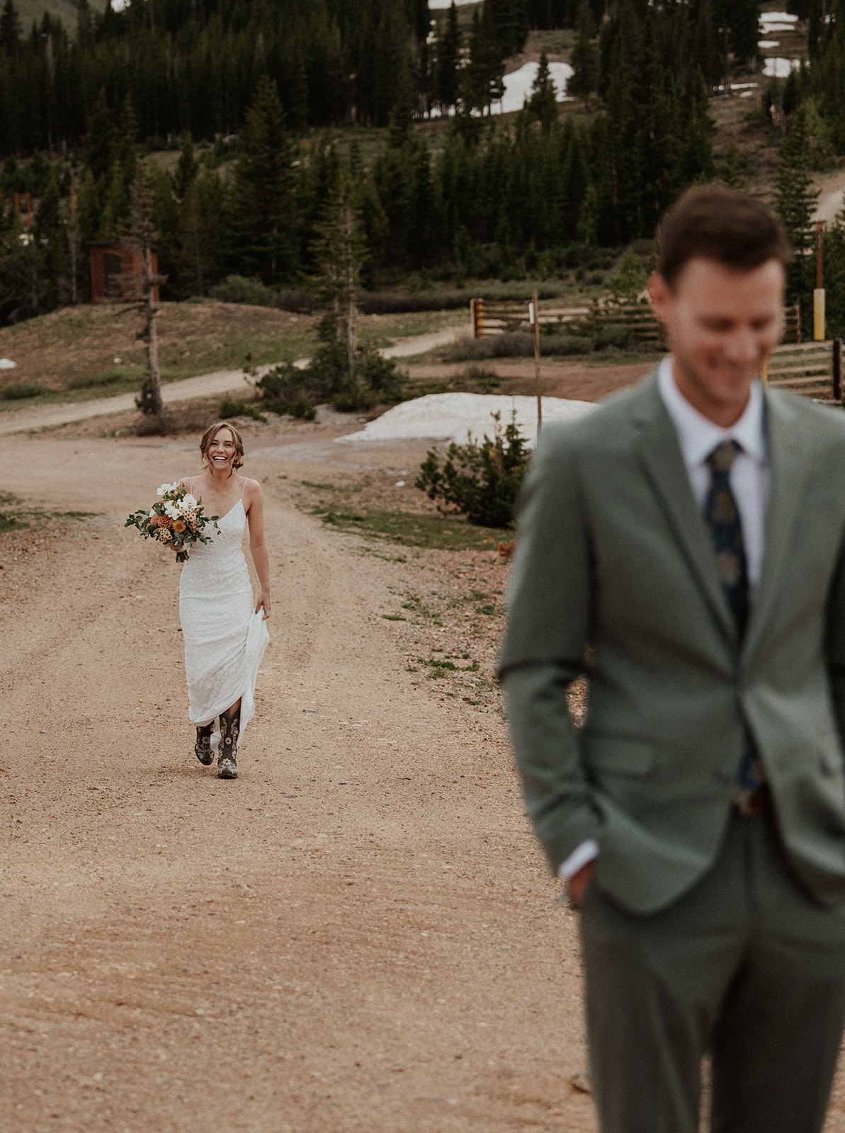 Bride walking up a dirt road to share her first look with her groom during their Colorado mountain elopement on Peak 9 in Breckenridge