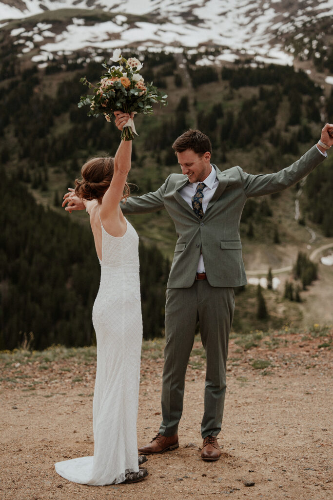 Bride and groom celebrating with their hands in the air during their Colorado mountain elopement on Peak 9 in Breckenridge 