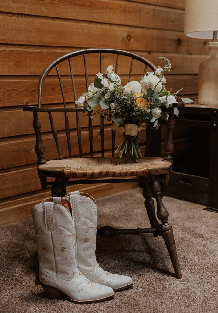 Colorado elopement details of a brides cowgirl boots and bouquet sitting on a chair