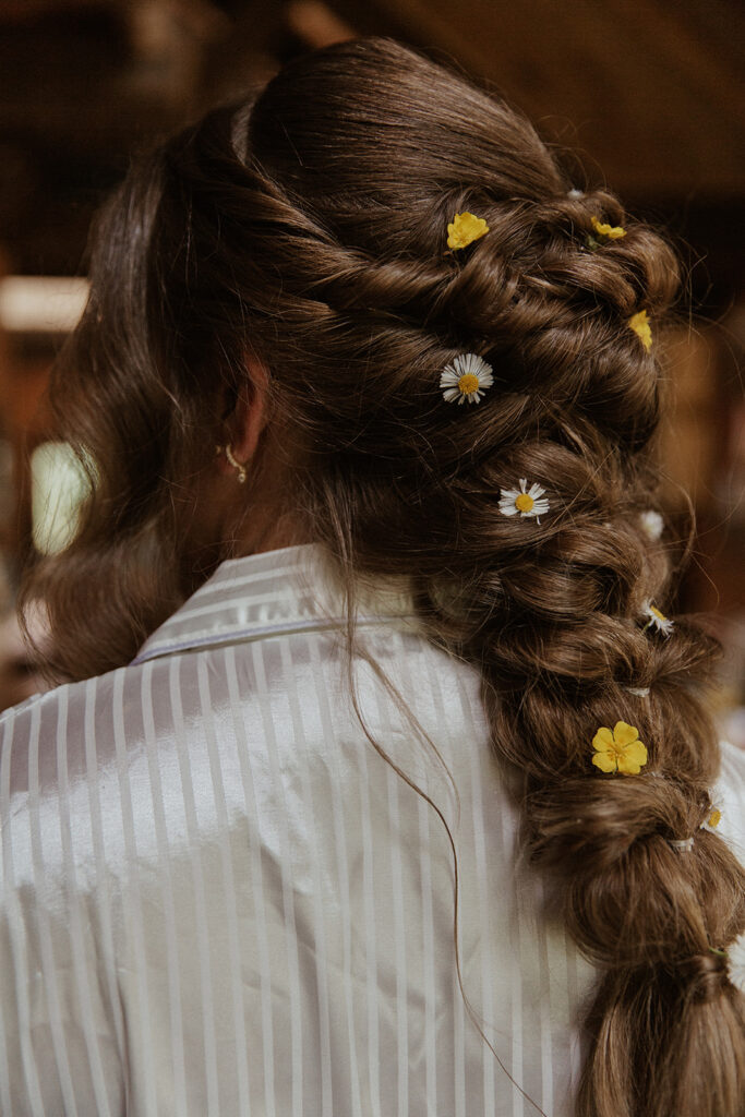 Brides mountain elopement hairstyle in an intricate braid adorned with white and yellow flowers