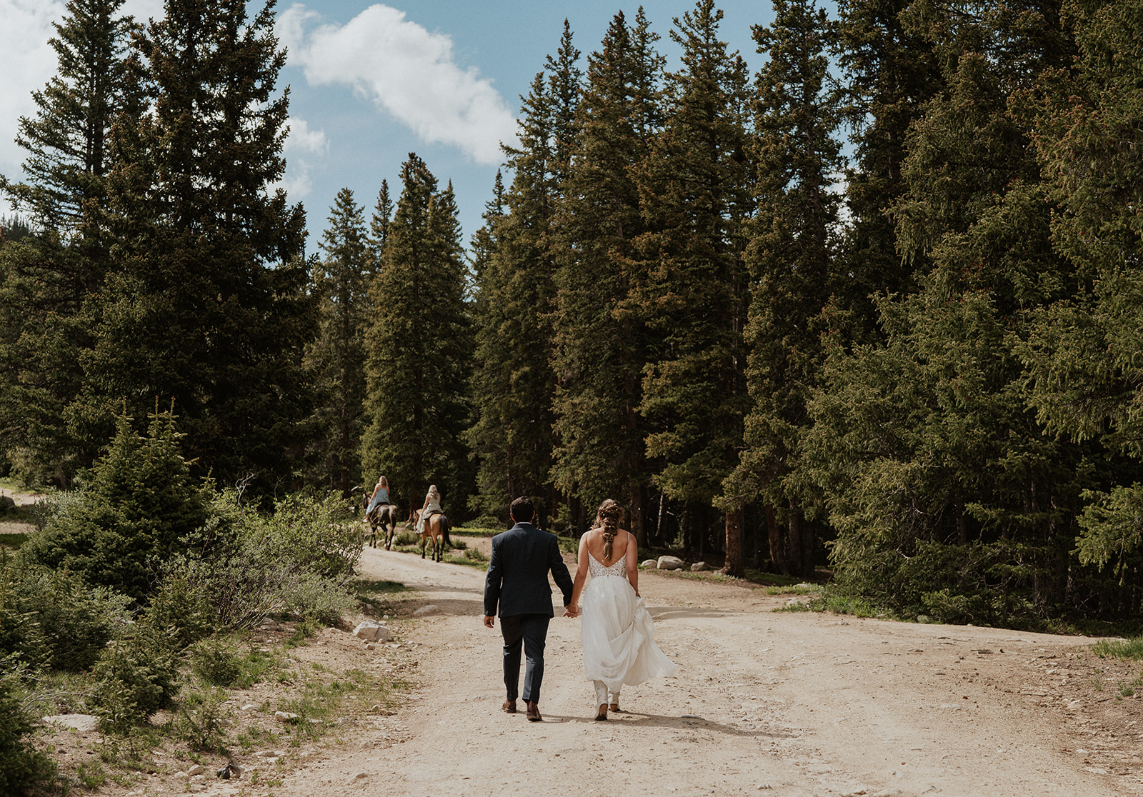 Bride ands groom holding hands and walking up a dirt road