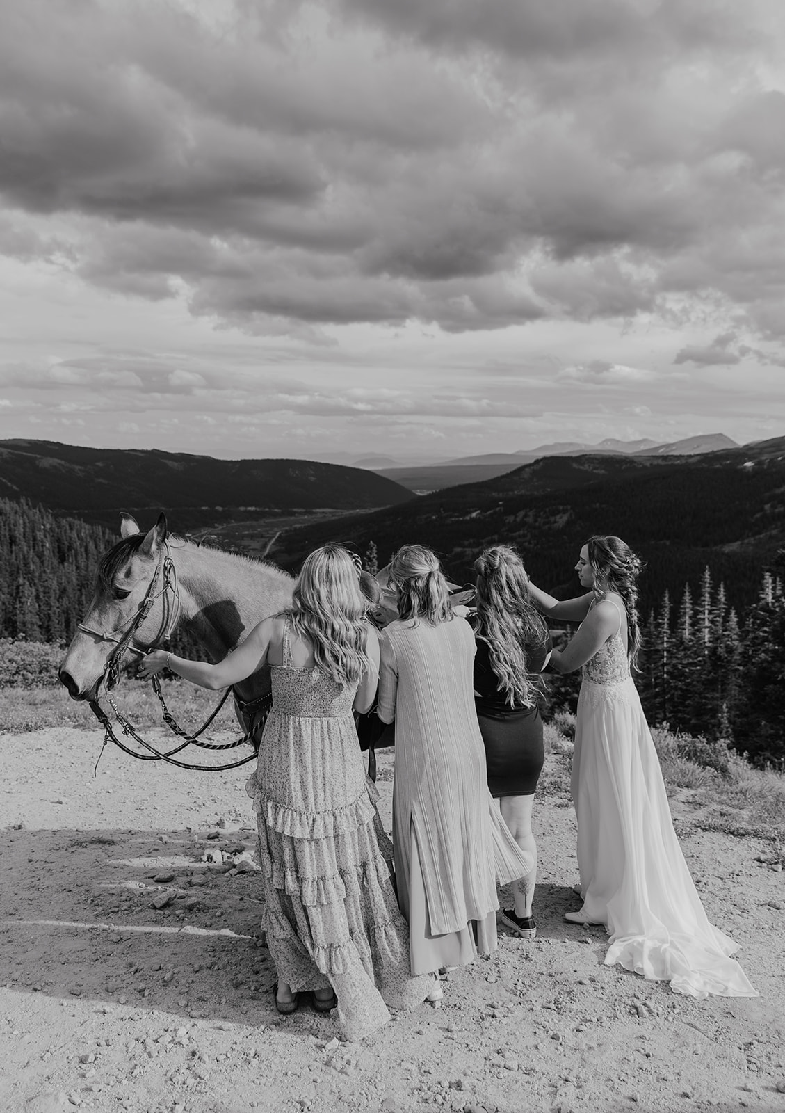 Black and white photo of a bride and her family getting her horse ready for horseback riding