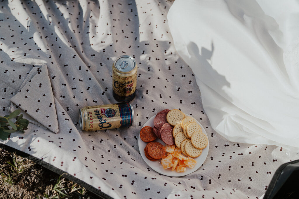 A mountain elopement picnic with beers, meat, cheese and crackers