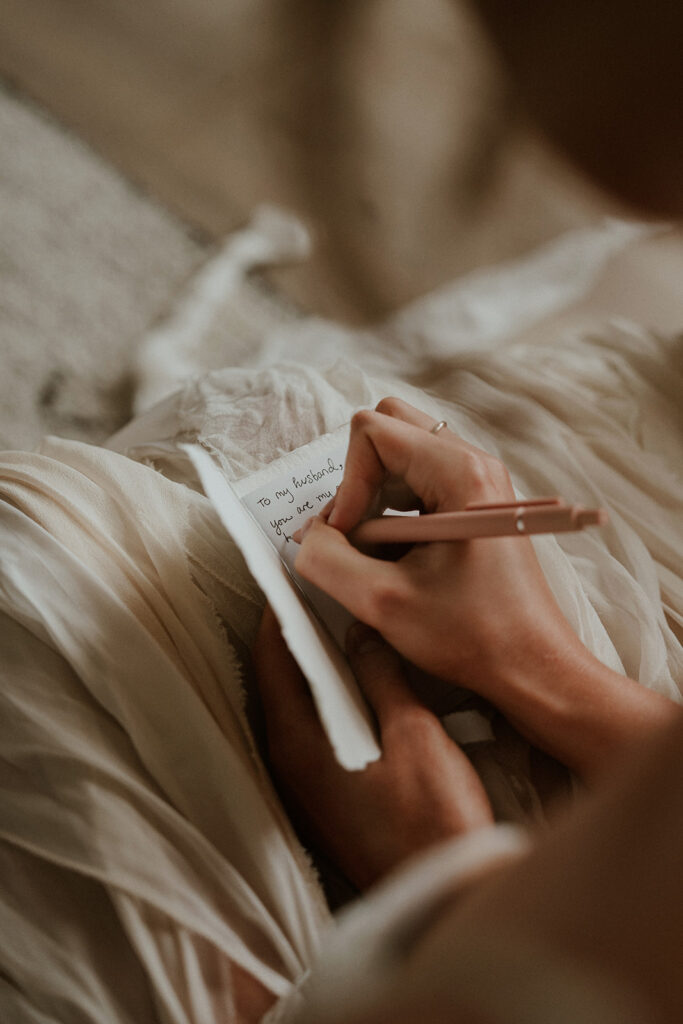 Bride writing in her white vow book before her intimate elopement in Alaska