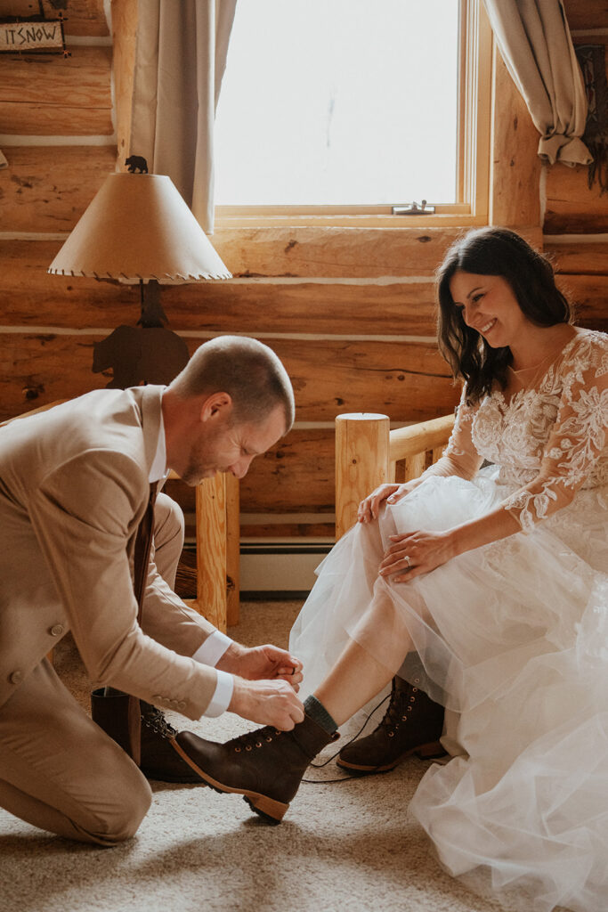 Groom helping tie the brides hiking boots for their Telluride, Colorado elopement