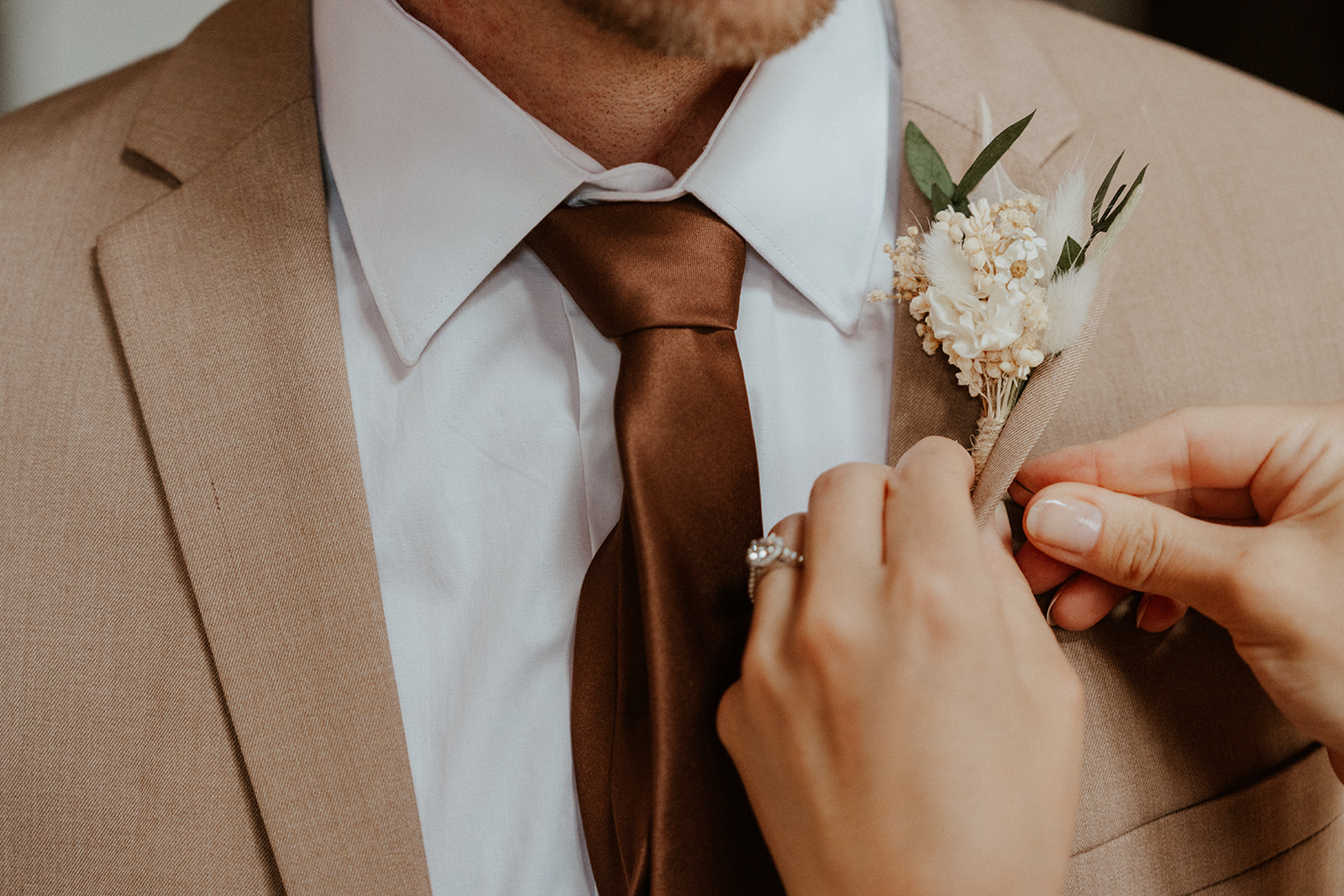 Bride helping a groom with his boutonniere 