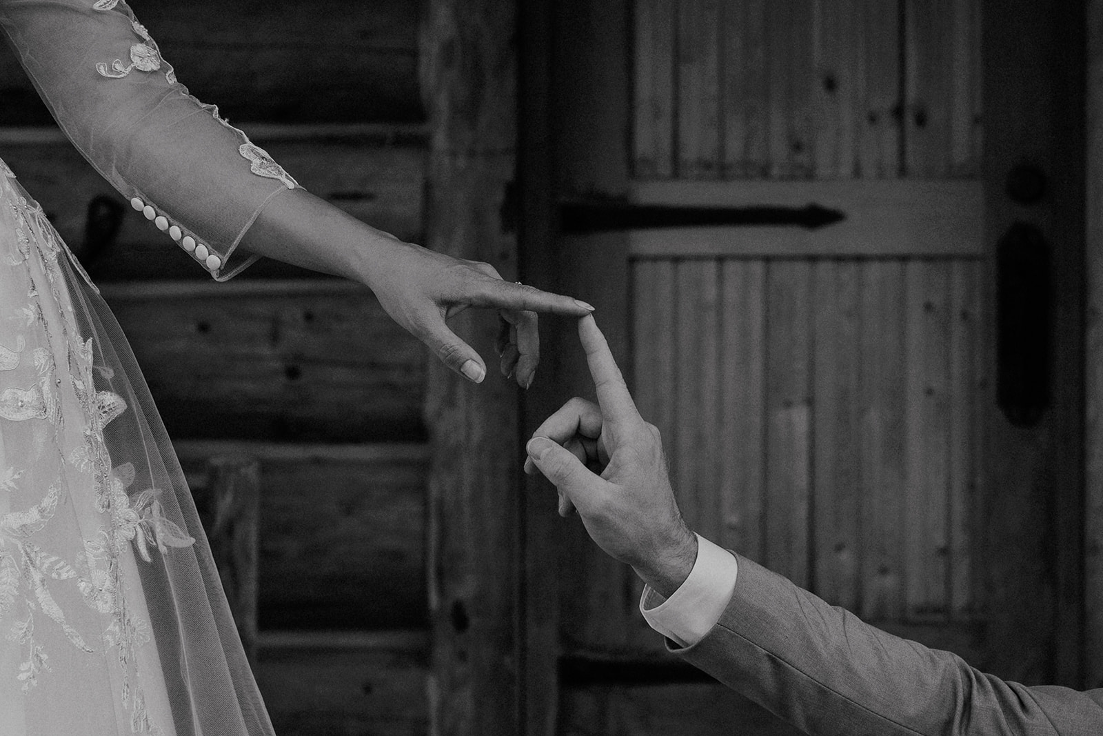 Black and white photo of a bride and groom touching fingers