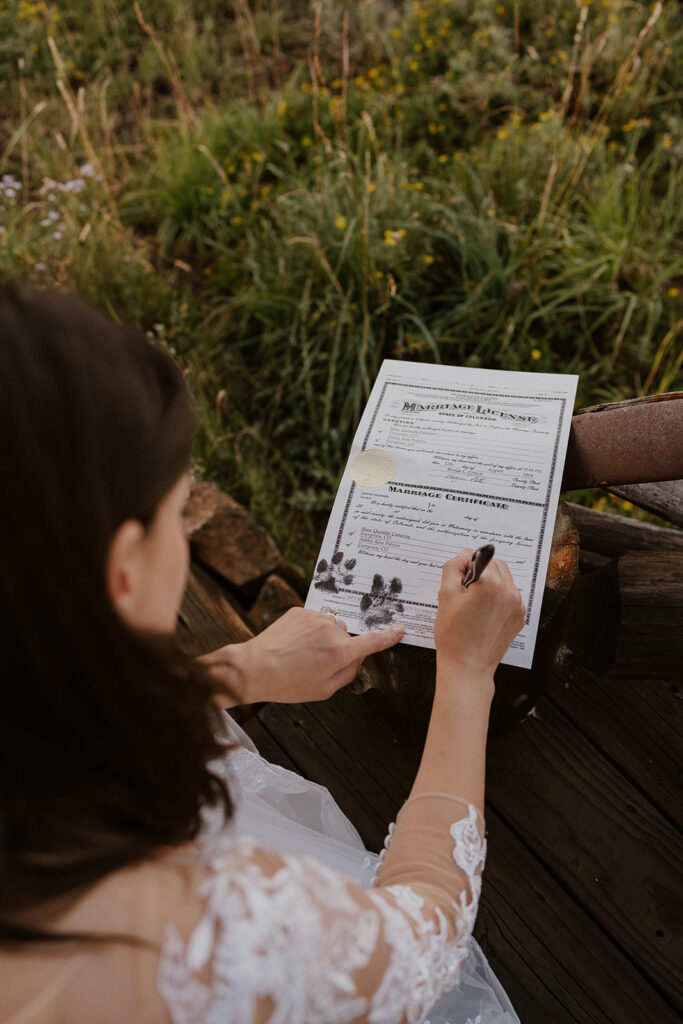 Bride and groom getting their marriage certificate signed with their dogs paw print in Telluride, Colorado