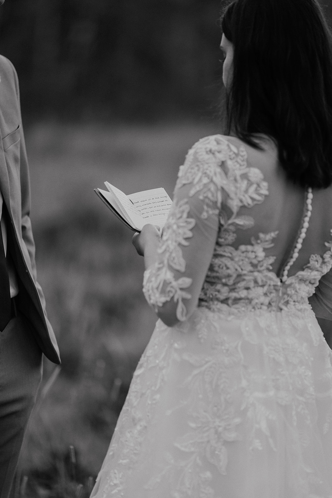 Black and white photo of a bride reading her vows to her groom