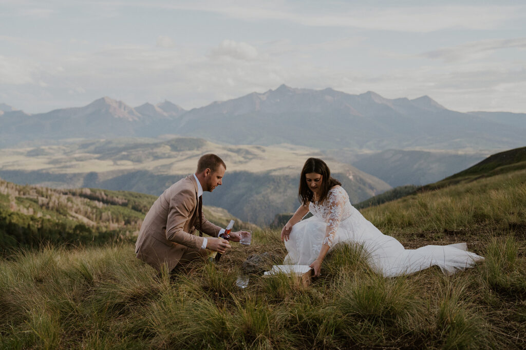 Bride and groom with a bourbon and pizza picnic in the mountains of Telluride, Colorado