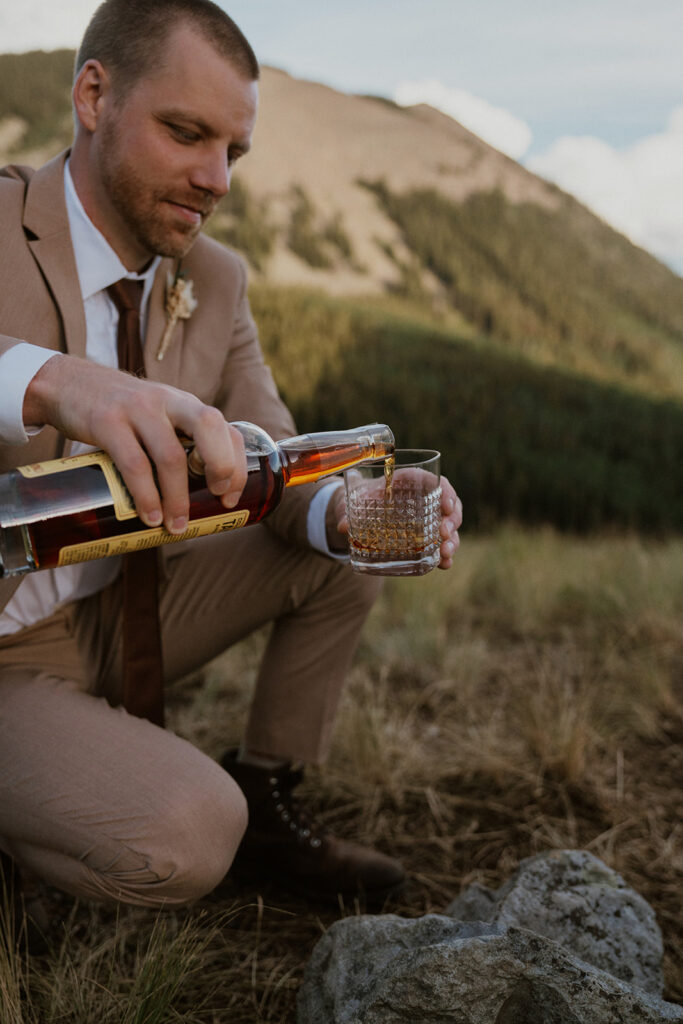 Groom pouring bourbon into a glass