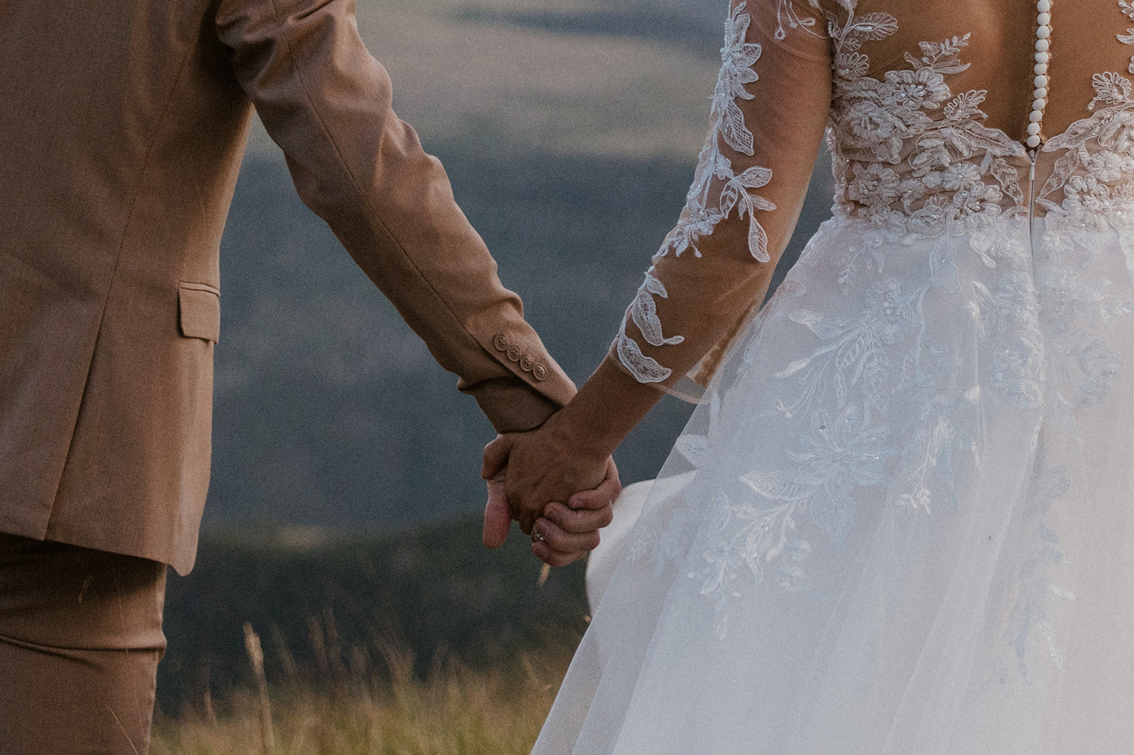 Bride and groom holding hands in the mountains