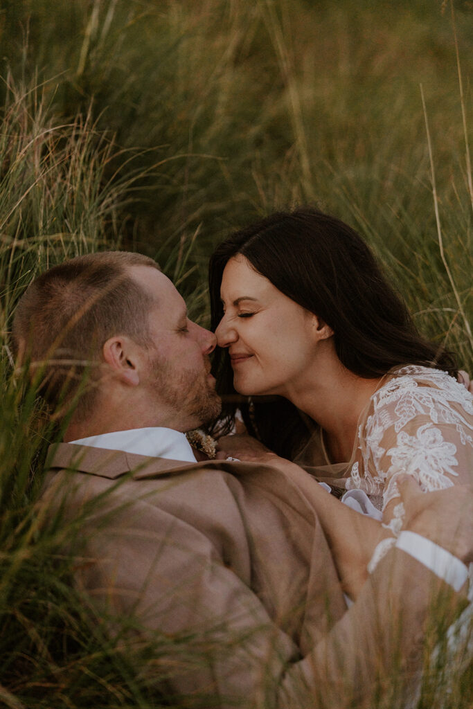 Bride and groom laying in the grass together