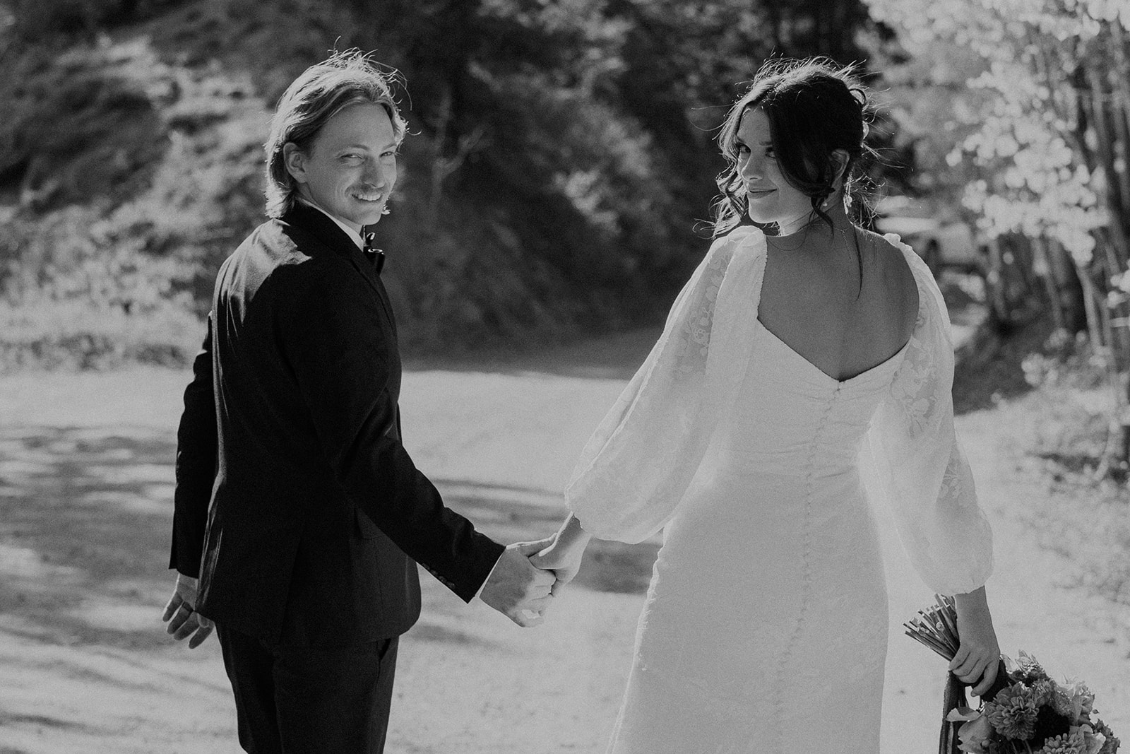 Black and white photo of a couple holding hands for their elopement