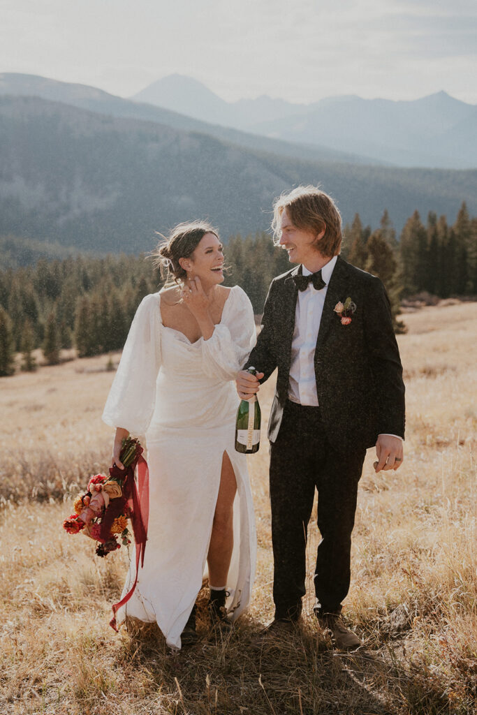 Bride and groom popping champagne in the mountains